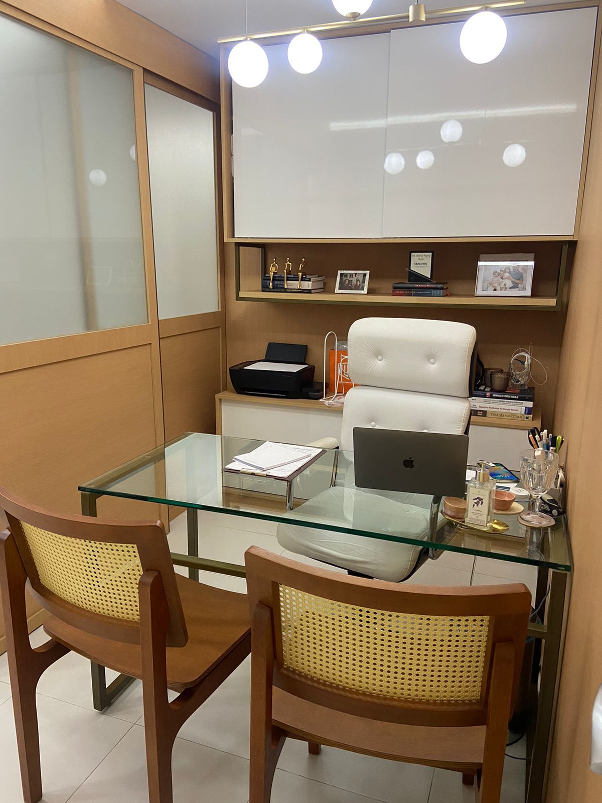 Consultório com mesa de vidro e cadeiras de madeira